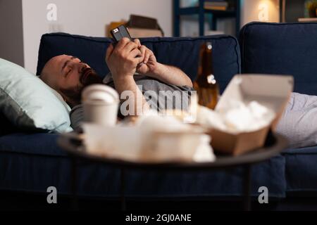 Triste malheureux malheureux seul déprimé déprimant homme surfant sur le smartphone, luttant avec la santé mentale passant par une dépression majeure. Angoissés et frustrés, les hommes lisant un avis de banque numérique Banque D'Images