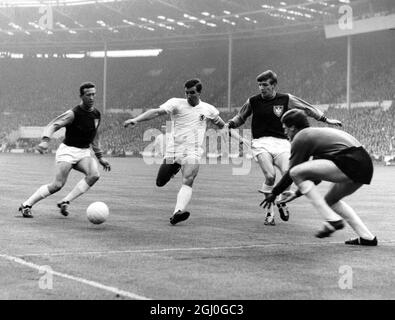 Finale de la coupe des vainqueurs de la coupe d'Europe à Wembley West Ham United v Munich le centre-avant de Munich, Rudi Brunnenmeier se tempête dangereusement entre le centre-moitié de West Ham, Ken Brown (à gauche) et la moitié droite, Martin Peters. Mais le gardien de but, Jim Standen, est bien placé pour sauver au stade Wembley. 19 mai 1965 Banque D'Images