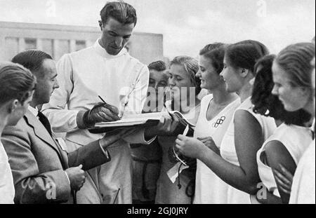 Jeux olympiques de 1936, Berlin - Giulio Gaudini, le gagnant italien d'escrime de foil et de sabre donne des autographes aux filles allemandes de gymnastique. (Giulio Gaudini, der italienische Florett-U. Sabelfechter giht den deutschen Turnerinnen Autogram.) (©TopFoto Banque D'Images