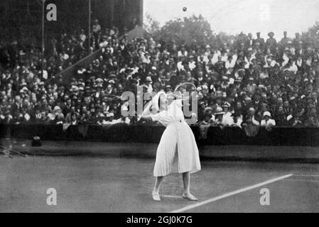 Défi des célibataires pour femmes : Mlle. Lenglen (challenger) au service en 1919. Suzanne Rachel flore Lenglen (24 mai 1899 - 4 juillet 1938) est une joueuse française de tennis qui a remporté 31 titres Grand Chelem de 1914 à 1926. Athlète flamboyante et tentatrice, elle a été la première célébrité féminine de tennis et l'une des premières stars internationales du sport féminin, nommée la Divine (la divine) par la presse française. ©TopFoto Banque D'Images