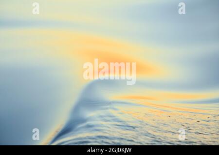 Coucher de couleurs et de motifs sur les petites vagues dans l'eau. Banque D'Images