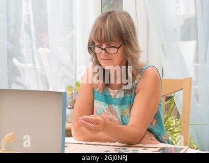 Une belle dame portant des verres se concentre dur regardant le couvercle de boîte d'une scie sauteuse choisir où placer une pièce de scie sauteuse Banque D'Images