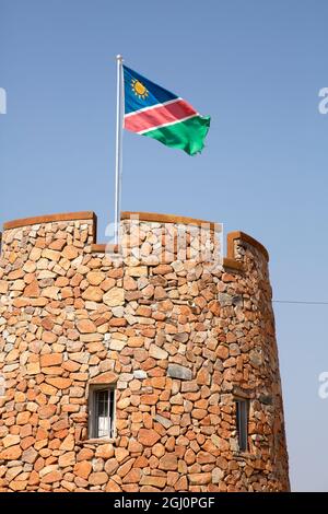 Afrique, Namibie, Parc national d'Etosha. Le drapeau namibien survole la tour de briques à l'entrée du parc. Credit AS: Wendy Kaveney / Galerie Jaynes / DanitaDelimo Banque D'Images