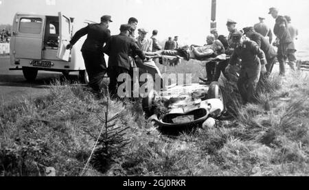 Le pilote de course italien , Luigi Musso , est transporté de sa Ferrari renversée par des hommes de la Croix-Rouge à l'ambulance d'attente après qu'il a dépassé une courbe et renversé au troisième tour , s'échapper sans blessures graves , Au cours de la course internationale de voiture de 1000 kilomètres à la célèbre piste ici . 56 voitures ont été inscrites dans la course de 12 pays et Mike Hawthorn conduite d'une Jaguar a été parmi le contingent britannique , Nuremberg , Allemagne . 27 mai 1956 Banque D'Images