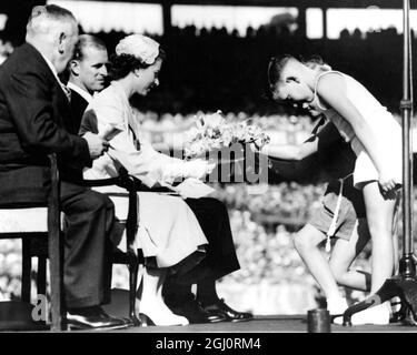 LA REINE DE TOURNÉE ROYALE AUSTRALIENNE REÇOIT UN POSI À MELBOURNE. LA REINE accepte une posy de BEVERLEY EMSLEY (10) et TREVOR REES (8) lors du rassemblement d'anciens militaires et de femmes au Melbourne Cricket Ground. Sur la gauche se trouve le président d'État de RSL N.D. WILSON. 3 mars 1954 Banque D'Images