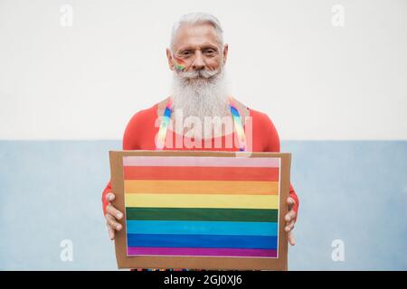 Hipster homme senior à la fierté gay tenant la bannière lgbt arc-en-ciel - Focus sur le visage Banque D'Images