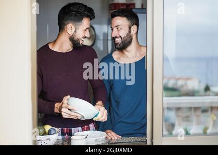 Gay couple masculin ayant le moment tendre tout en lavant des plats à l'intérieur de la cuisine maison - Focus sur le visage gauche de l'homme Banque D'Images