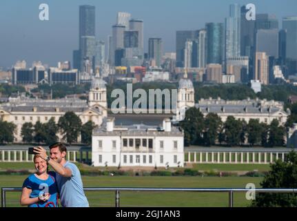 Deux personnes prennent un selfie devant les gratte-ciel de Londres depuis l'observatoire de Greenwich, dans le parc de Greenwich, car de nombreuses parties du Royaume-Uni sont sur le point de connaître une nouvelle journée de températures élevées, tandis que le début chaud de septembre se poursuit. Date de la photo: Mercredi 8 septembre 2021. Banque D'Images