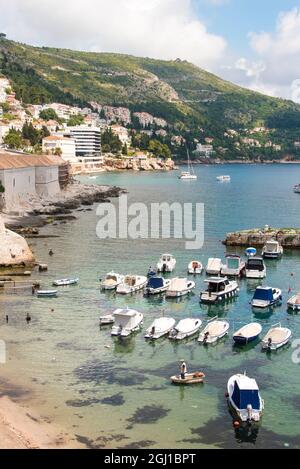 Croatie, Dubrovnik. Vue sur la marina et la côte depuis le mur de la vieille ville. Le pêcheur se tient en bateau à l'approche de la rive. Banque D'Images