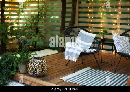 Véranda de la maison avec fauteuil Acapulco noir et pots de plantes. Espace confortable dans le patio ou le balcon avec guirlande. Véranda intérieure en bois avec mobilier. Banque D'Images