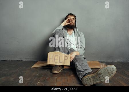 Le bum barbu est assis sur le sol et porte un panneau aide à la dépression style de vie Banque D'Images