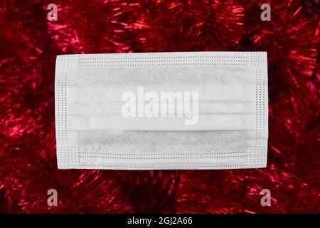 Flat Lay festive décoration de noël et masque de protection médicale du visage sur fond rouge scintillant, Noël et nouvel an, Au revoir 2020, New normal yea Banque D'Images