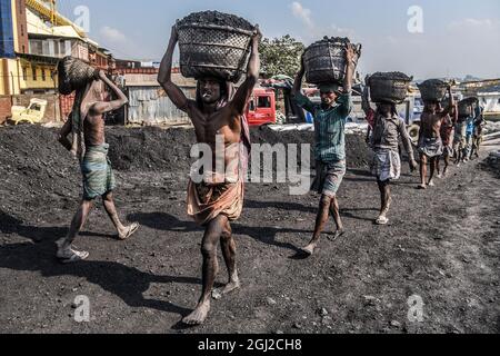 Hommes et femmes travailleurs quotidiens déchargeant des charbons de petits navires dans la ville portuaire du fleuve Karnabuli, Chittagong, Bangladesh. Banque D'Images