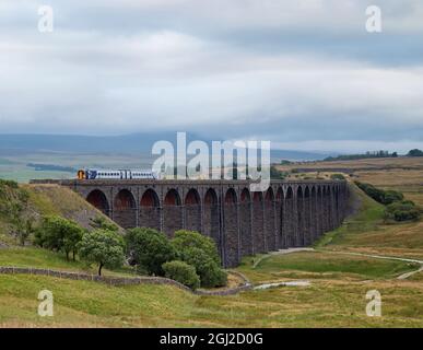 Un train diesel traversant le viaduc de Ribblehead, avec des nuages éloignés sur les sommets des Yorkshire Dales Banque D'Images