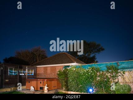 Jardin à l'arrière la nuit montrant des lumières solaires, des meubles de jardin et des étoiles dans le ciel clair en été en Angleterre, Royaume-Uni. Banque D'Images