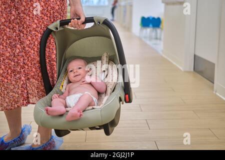 Une femme mère porte bébé dans un siège d'auto pour bébé dans une clinique Banque D'Images