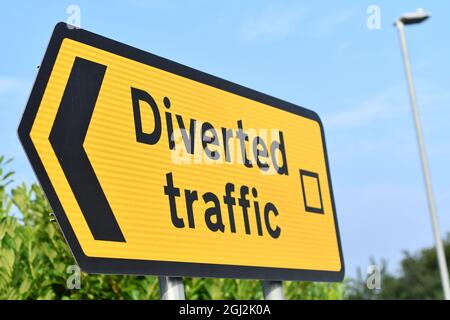 Vue inclinée d'un panneau de direction de circulation routière en jaune indiquant trafic dirigé avec un ciel bleu en arrière-plan Banque D'Images