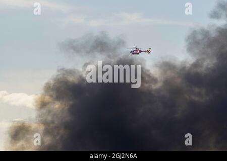 Kidderminster, Royaume-Uni. 8 septembre 2021. Un énorme incendie a éclaté dans Park Street, Kidderminster, dans les unités industrielles derrière les pneus ATS. Les pompiers sont sur les lieux, mais on peut voir de la fumée noire qui orne les lieux à des kilomètres de là. Une ambulance aérienne peut être vue passant par de grands nuages de fumée noire de l'incendie. Credit Lee Hudson/Alay Live News Banque D'Images