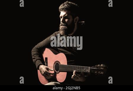 Pièces de guitariste barbu. Jouer de la guitare. Un homme de style hippster qui s'assoit dans un pub. Musique live. Guitares et cordes Banque D'Images