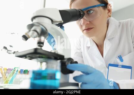 Portrait d'une scientifique féminine regardant au microscope en laboratoire Banque D'Images