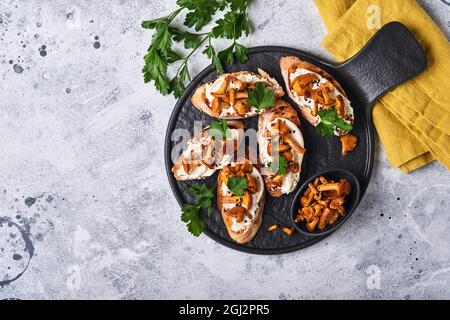 Sandwichs chanterelle au fromage. Sandwich ouvert avec fromage crémeux, assaisonnements, poivre et persil frais sur un fond de bois ancien. Faux Banque D'Images