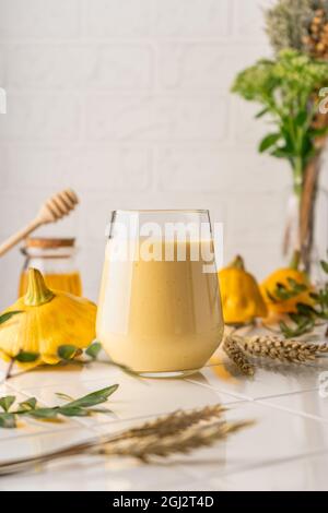 smoothie naturel à base de citrouille jaune. boisson d'automne au miel et au lait. sur fond clair, position verticale Banque D'Images