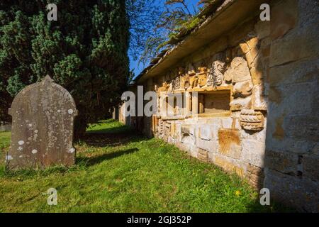 Des fragments de pierres sculptées de l'abbaye de Hailes sont incrustés dans le mur du cimetière de l'église Saint-Pierre, à côté de Stanway House, Cotswolds, en Angleterre Banque D'Images