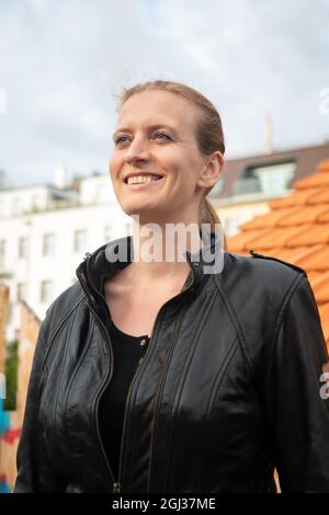 portrait d'une femme blonde en cuir noir blouson debout à l'extérieur et souriant Banque D'Images