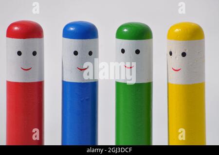 Jouet escamotable en bois pour tout-petit.Quatre personnes en bois multicolore avec des visages heureux sur un fond blanc Banque D'Images