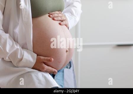 grossesse en santé. Vue latérale femme enceinte avec grand ventre grossesse avancée dans les mains. Espace de copie de bannière pour le texte. Élégante mère en attente de bébé. Banque D'Images