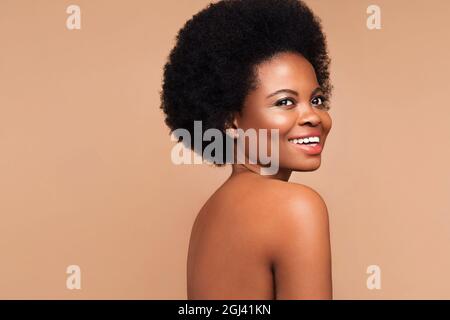 Portrait d'une femme africaine aux cheveux bouclés, au sourire blanc, à la peau propre et au maquillage parfaits pour le type de peau Banque D'Images