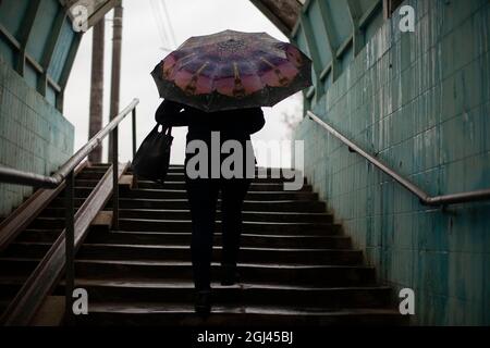 Une femme avec un parapluie va à l'extérieur. La femme monte les escaliers. Passage souterrain pour piétons. Temps pluvieux dans la ville. Banque D'Images