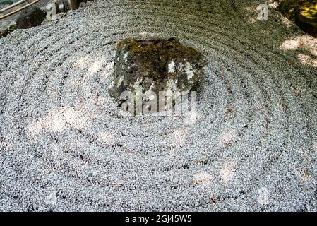 Photo d'une partie d'un jardin zen de style asiatique avec des cercles rayés autour d'une pierre principale. Banque D'Images