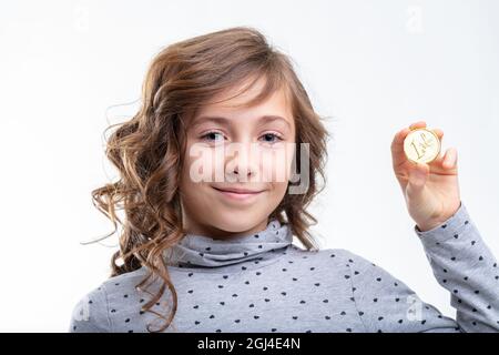 Petite fille tenant une pièce d'un euro avec un sourire heureux dans un portrait de gros plan isolé sur blanc Banque D'Images