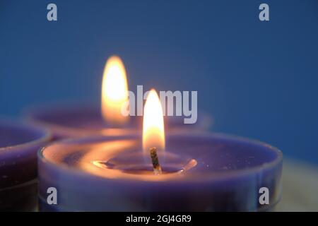 Flamme de bougie.ensemble de bougies bleues dans l'obscurité.symbole de religion. Fond de bougies. Bougies bleues sur fond bleu Banque D'Images