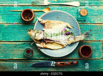 Poisson cuit dans les herbes et le foin de prairie. Bar de mer rôti, vue de dessus Banque D'Images