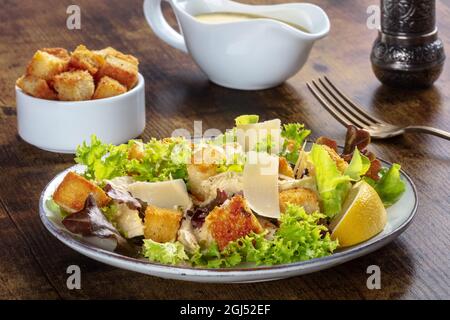 Salade César au poulet avec sauce classique à base de mayonnaise, croûtons et poivre, sur fond de bois rustique foncé Banque D'Images