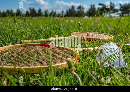 gros plan, des raquettes de tennis pour le badminton et un shuttlecock se trouvent sur l'herbe verte dans un pré, dans une clairière, dans la nature sur le fond des arbres Banque D'Images