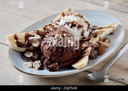 De délicieux boules de chocolat et de glace à la vanille servis sur l'assiette avec des tranches de banane décorées de noix et de sirop Banque D'Images