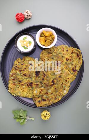 Une nourriture appelée Methi paratha ou Methi thepla est un plat de petit déjeuner indien servi avec du raita de boondi caillé et du sabzi de capsicum.Masala Fenugreek roti. Banque D'Images