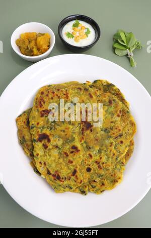 Une nourriture appelée Methi paratha ou Methi thepla est un plat de petit déjeuner indien servi avec du raita de boondi caillé et du sabzi de capsicum.Masala Fenugreek roti. Banque D'Images