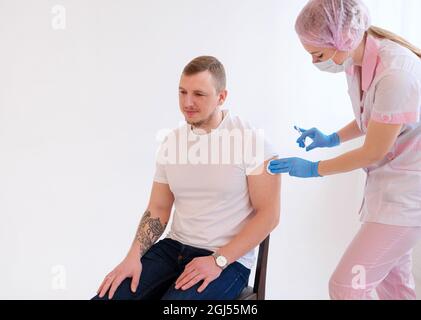 Vaccination Covid-19. Homme de race blanche se faire vacciner contre le coronavirus recevant le vaccin Covid injection intramusculaire pendant l'AP du médecin Banque D'Images