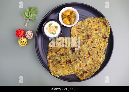 Une nourriture appelée Methi paratha ou Methi thepla est un plat de petit déjeuner indien servi avec du raita de boondi caillé et du sabzi de capsicum.Masala Fenugreek roti. Banque D'Images