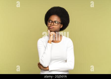 Femme africaine pensive pensant regarder loin toucher la main sur le menton ponder prendre la décision sur le mur de studio Banque D'Images