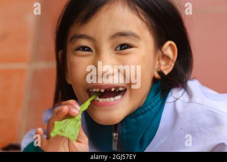 une jeune fille rit avec des dents décalées et de la moutarde sur sa main Banque D'Images