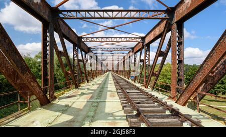 Ancienne ligne de chemin de fer traversant un pont rouillé transformé en voie de plaisance pour le train-cycle draisine avec quatre roues. Banque D'Images