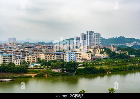 Petits bâtiments de la ville de comté et pont arc-en-ciel de l'autre côté de la rivière à Guangxi, en Chine Banque D'Images