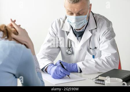 Covid-19, prévention des virus, personnel de santé et concept de vaccination. Médecin homme sérieux et confiant, en manteau blanc et masque médical, portant des lunettes, Banque D'Images