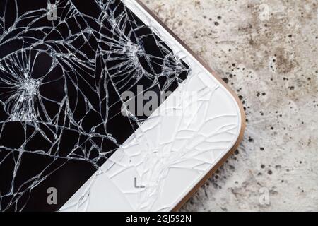 Un smartphone dont l'écran est cassé est couché sur le béton. Gros plan, mise au point sélective Banque D'Images