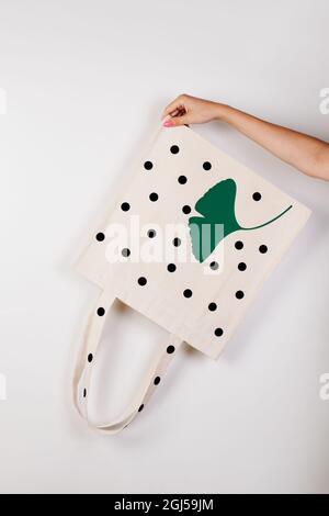 Sac écologique en coton. La main de la femme Mockup tient le sac écologique blanc inversé avec imprimé sur fond blanc isolé pour le texte ou le design, concept de Banque D'Images